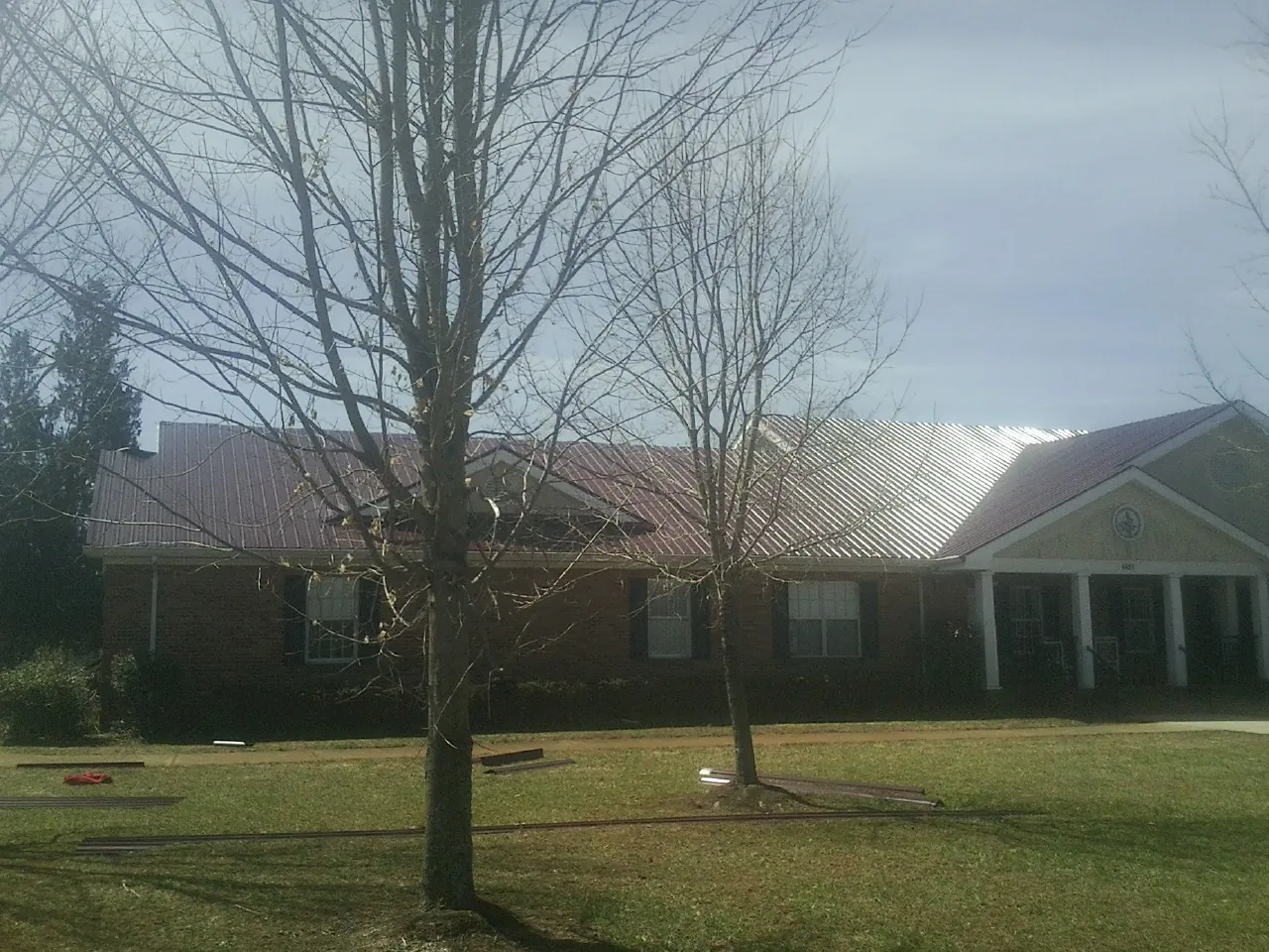 Red metal roof on a brick building seen from the front lawn in Gates