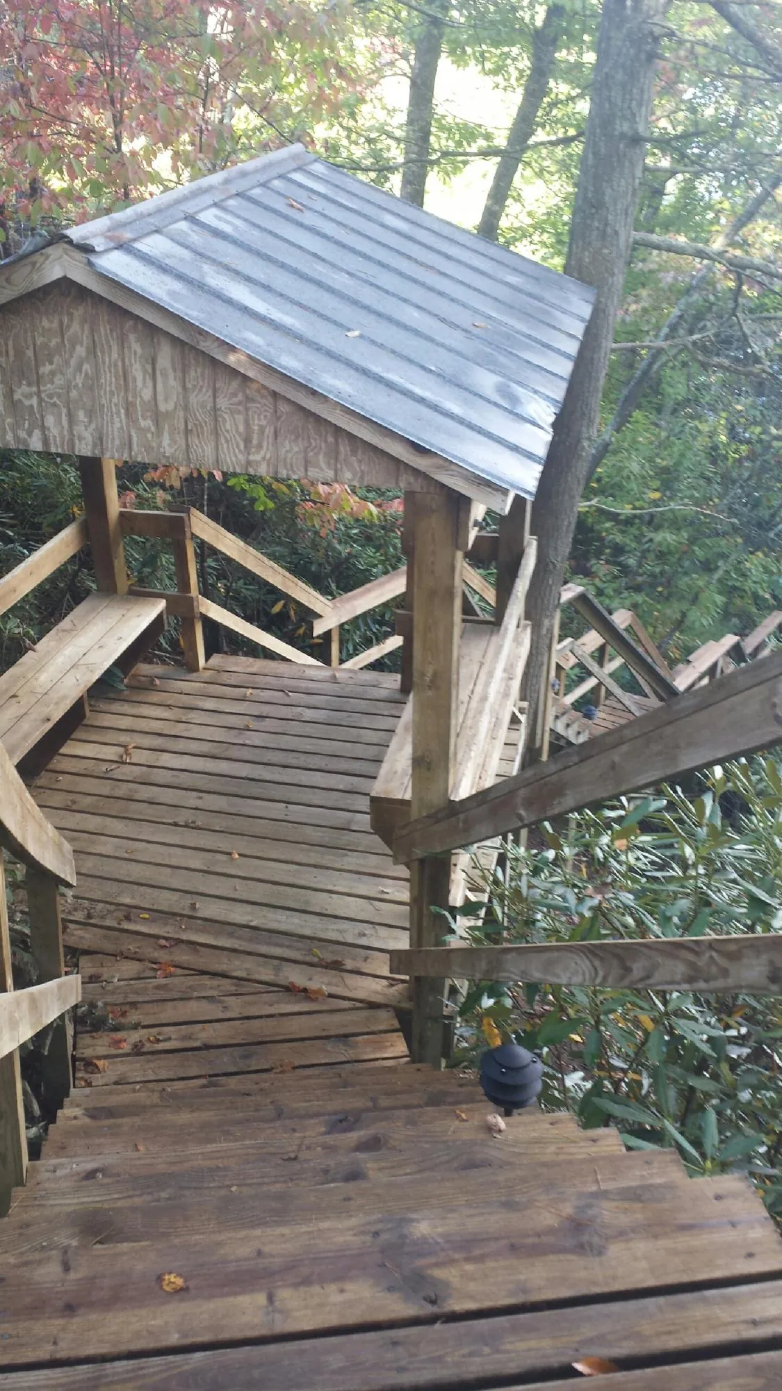 Metal roofed shelter over wooden steps on a wooded walkway — Skylight Repair & Installation work by our crew in Gates